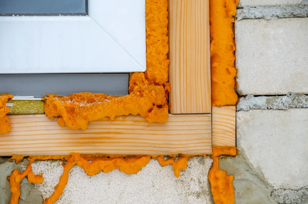Montageschaum füllt die Fuge zwischen einem neuen Fensterrahmen und dem Mauerwerk.